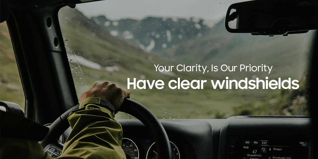 Person driving a vehicle with text overlay 'Your Clarity, Is Our Priority Have clear windshields'.